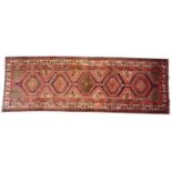A thick pile Persian Heriz runner, in red, blue and ivory colourways, with five linked geometric