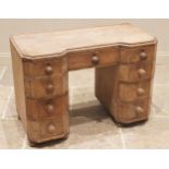 An Art Deco pine kneehole desk, of inverted breakfront form with canted corners, the central