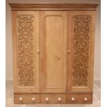 A Victorian pine triple wardrobe, the moulded cornice above three doors, the plain panelled centre