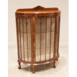 A 1930's figured walnut bowfront display cabinet, with a rear gallery over a single convex door