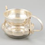 Silver tea strainer with hinged drip tray.