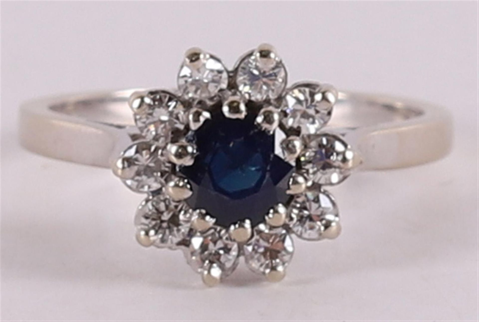 A 14 kt gold ring with a round facet cut blue sapphire and brilliant cut diamond