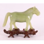 A green jade horse on a tropical wooden loose pedestal, China, around 1900.