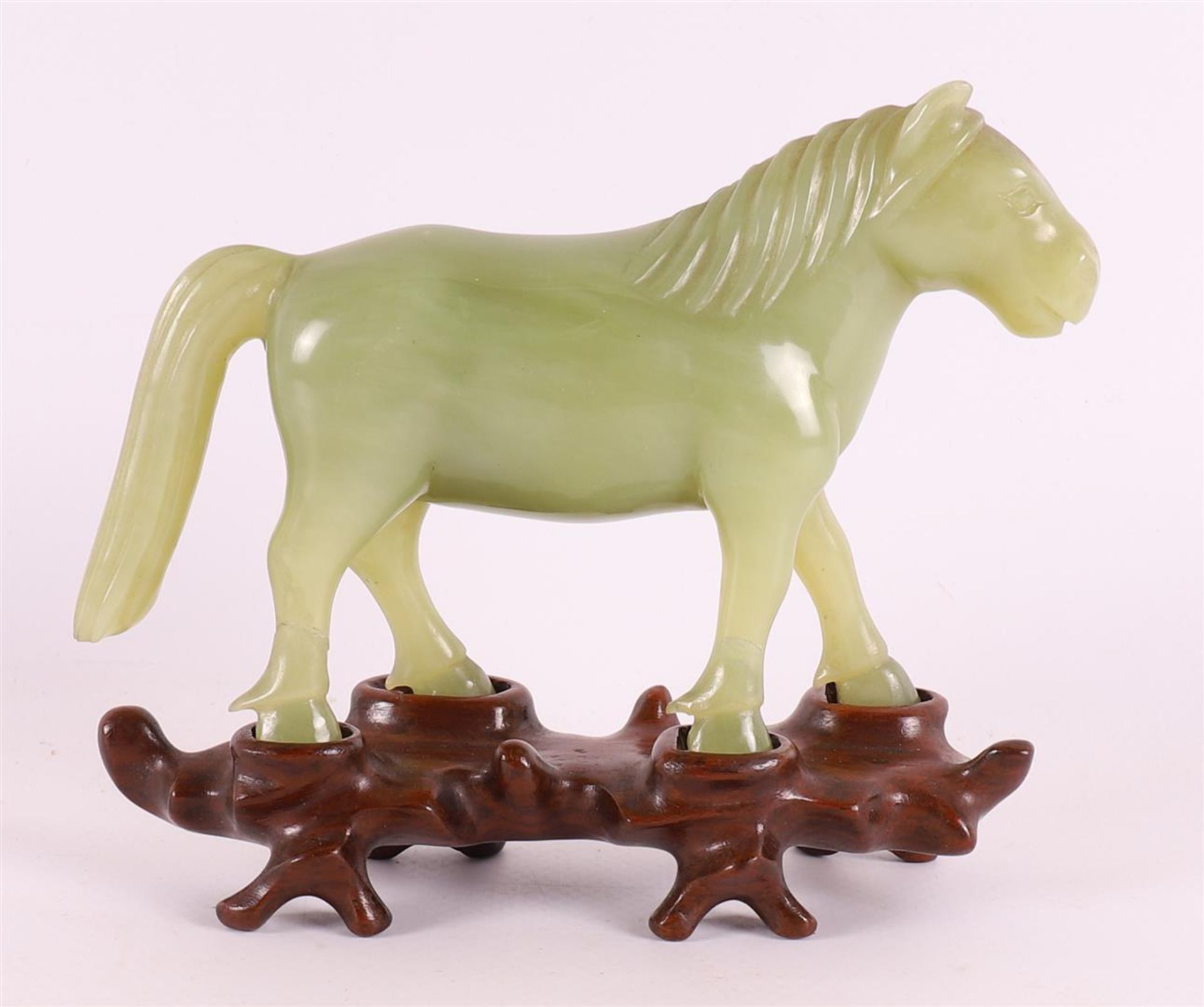 A green jade horse on a tropical wooden loose pedestal, China, around 1900.