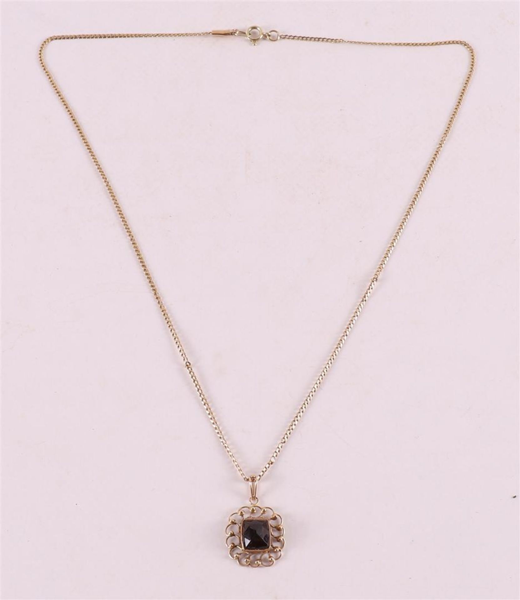 A 14 kt 585/1000 gold square pendant with garnet, on a gold necklace.