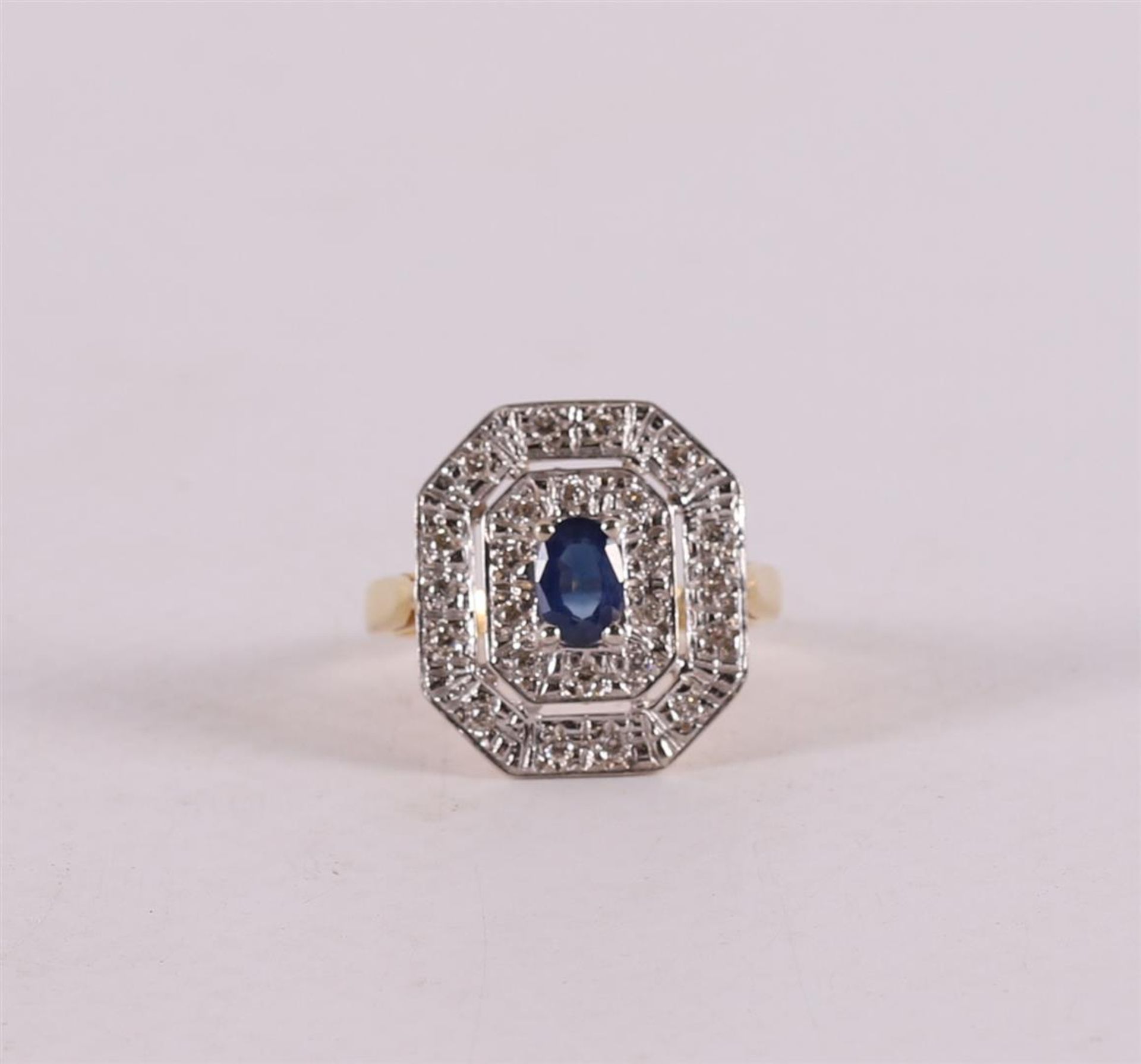 An 18 kt gold ring with a facet cut blue sapphire and 24 diamonds