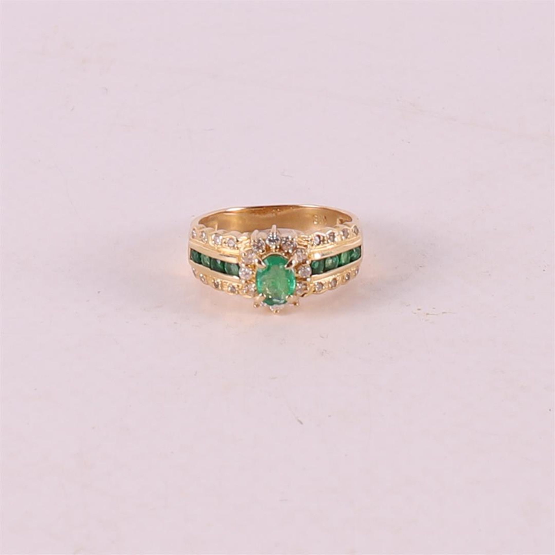 An 18 kt 750/1000 yellow gold ring set with green emerald and 28 diamonds.