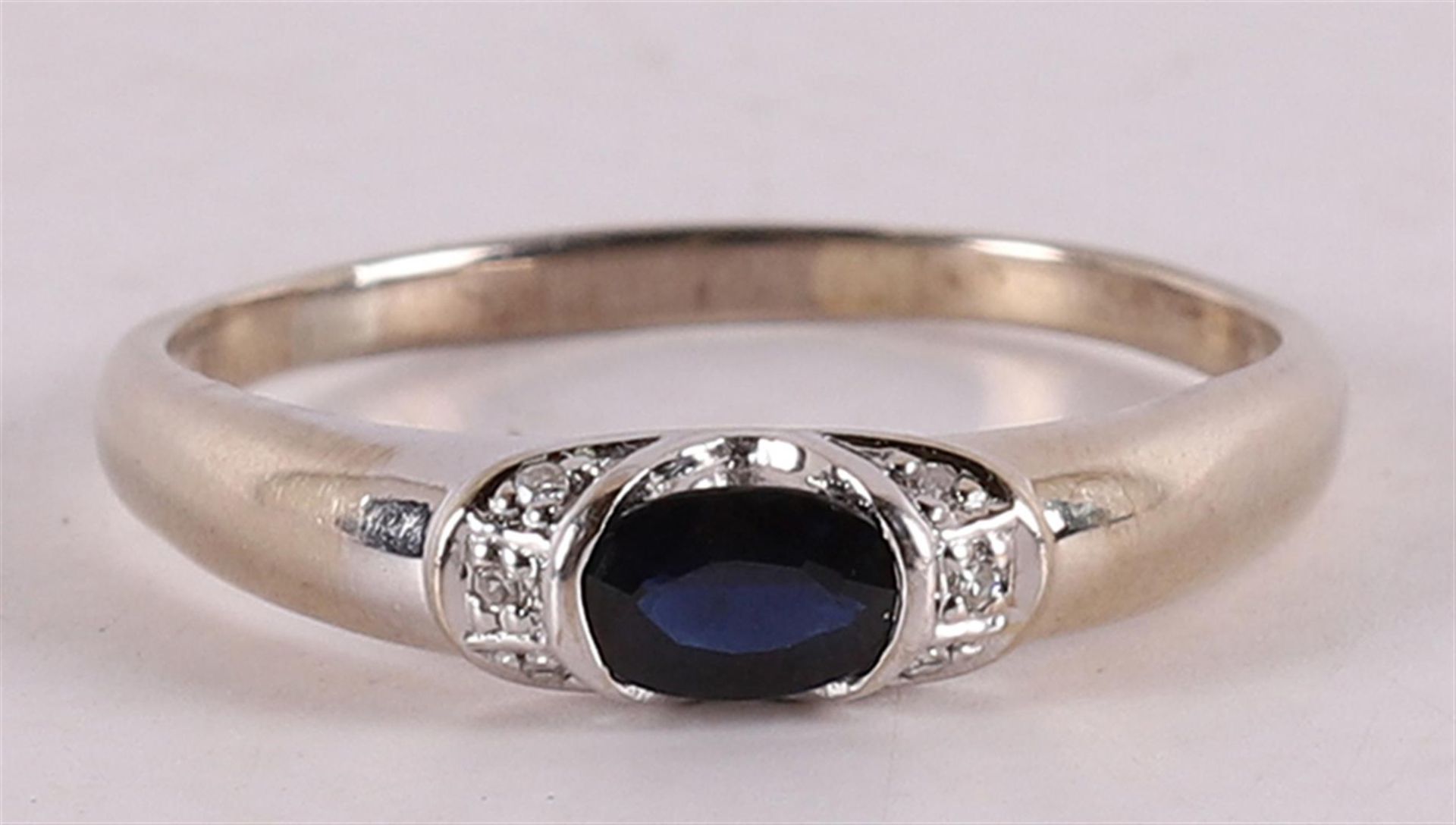 A 14 kt gold ring with an oval faceted blue sapphire and diamonds.
