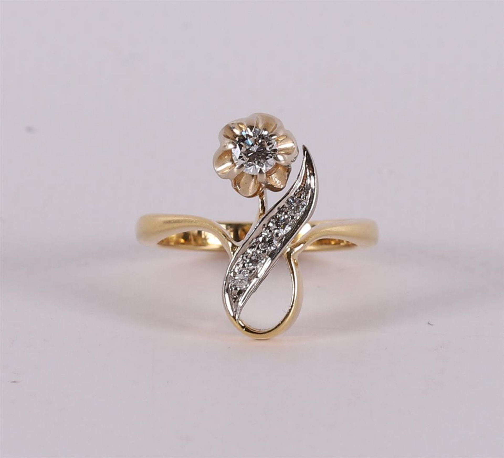 An 18 carat gold ring in the shape of a flower with a brilliant.