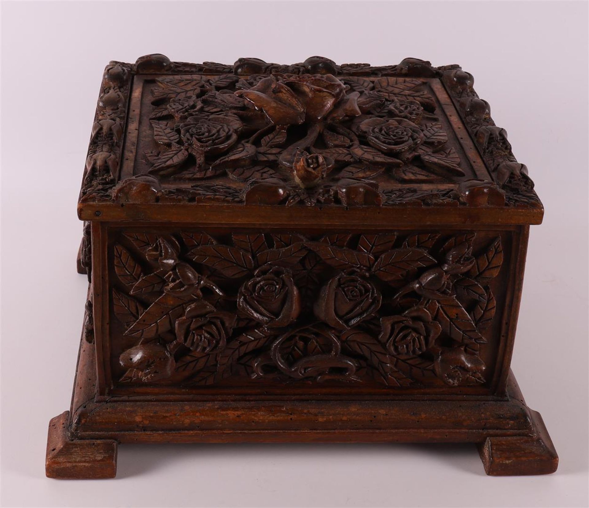 A carved wooden lidded box with relief decoration of roses, around 1900.