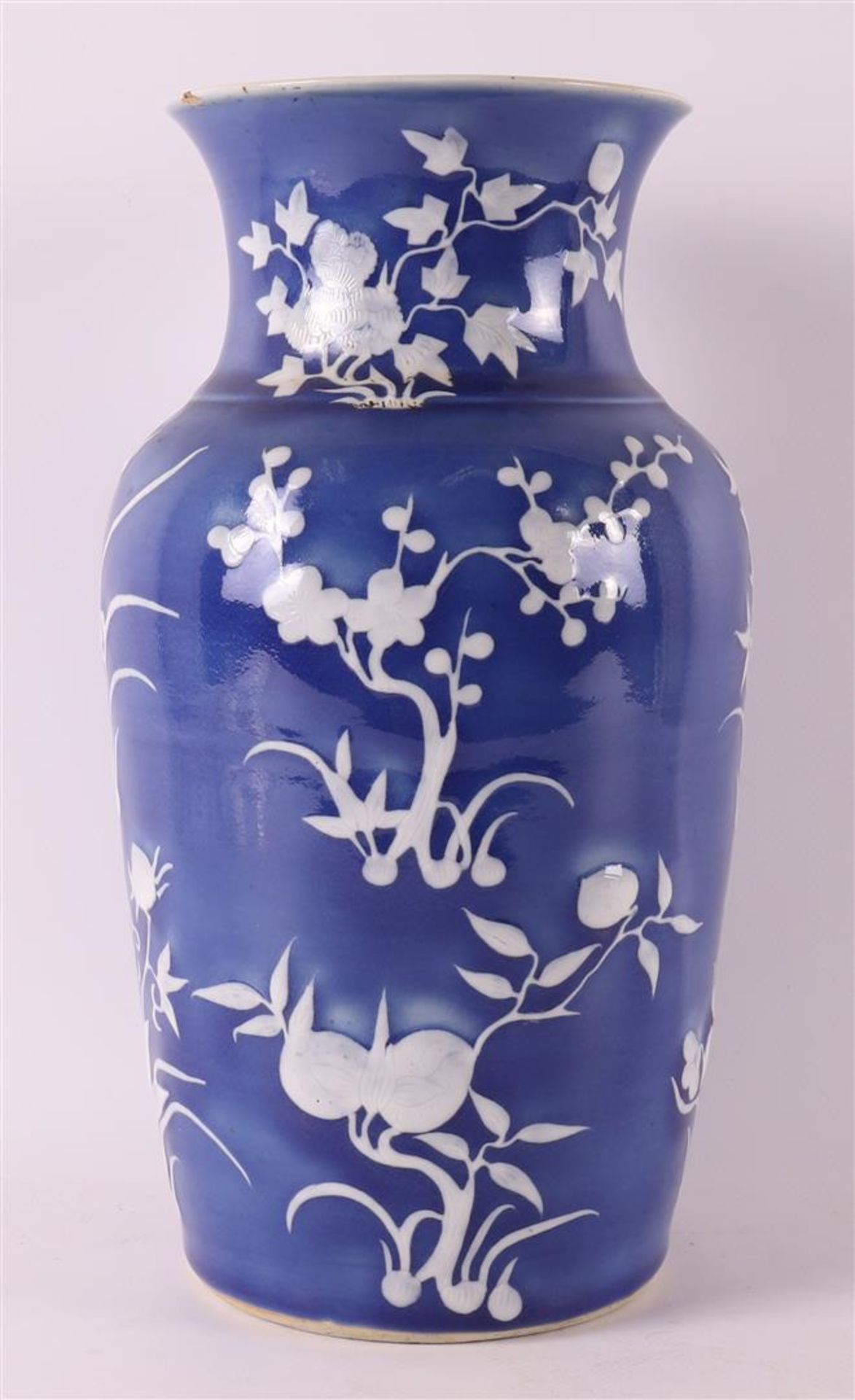 A porcelain vase with white relief floral decoration on a blue background, China