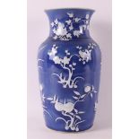 A porcelain vase with white relief floral decoration on a blue background, China