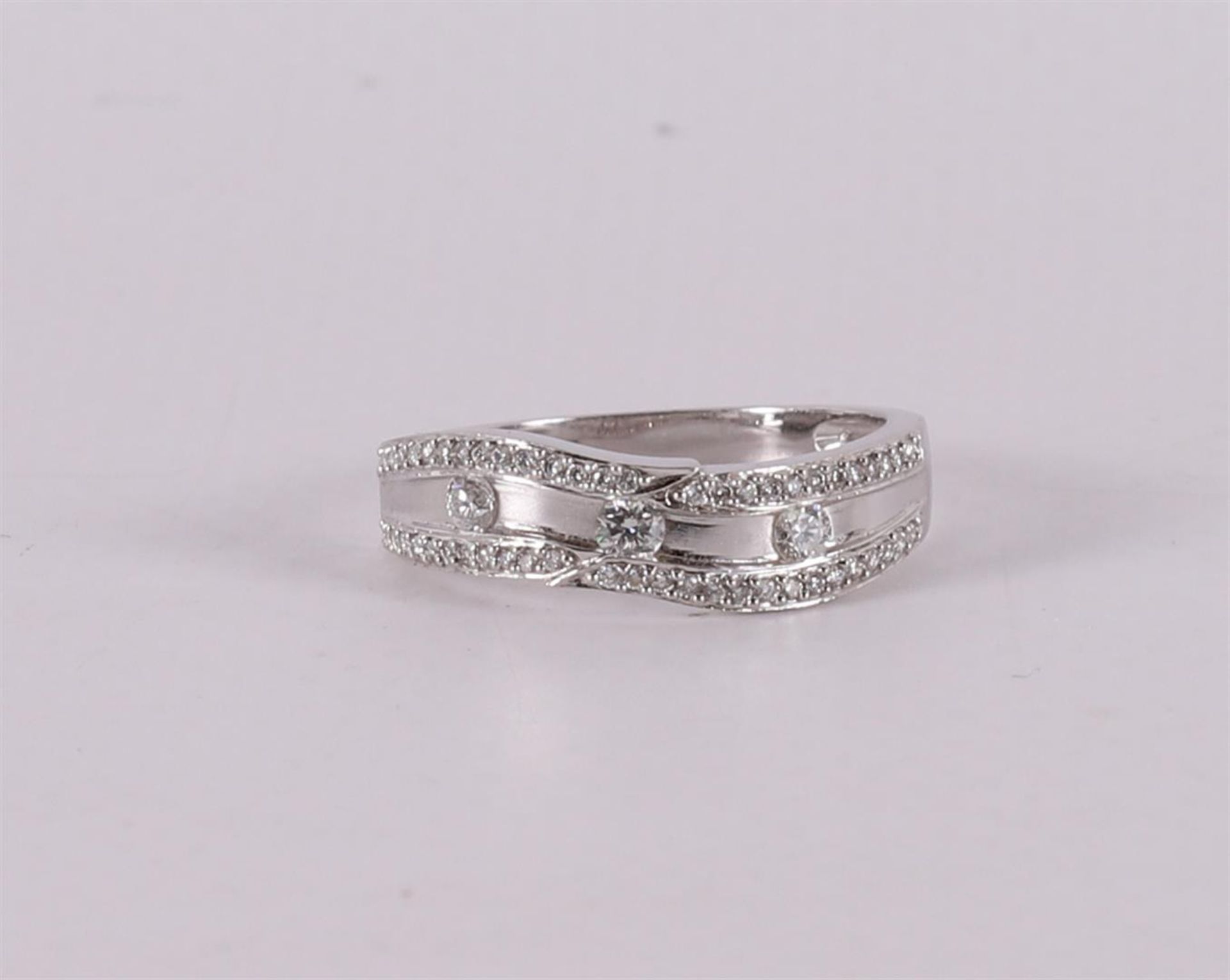 An 18 kt white gold band ring with 3 brilliants and 54 smaller ones.