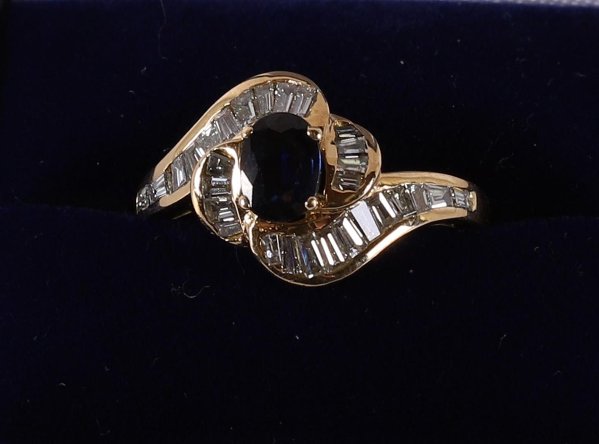 An 18 kt gold women's ring, set with oval cut blue sapphire and diamond.