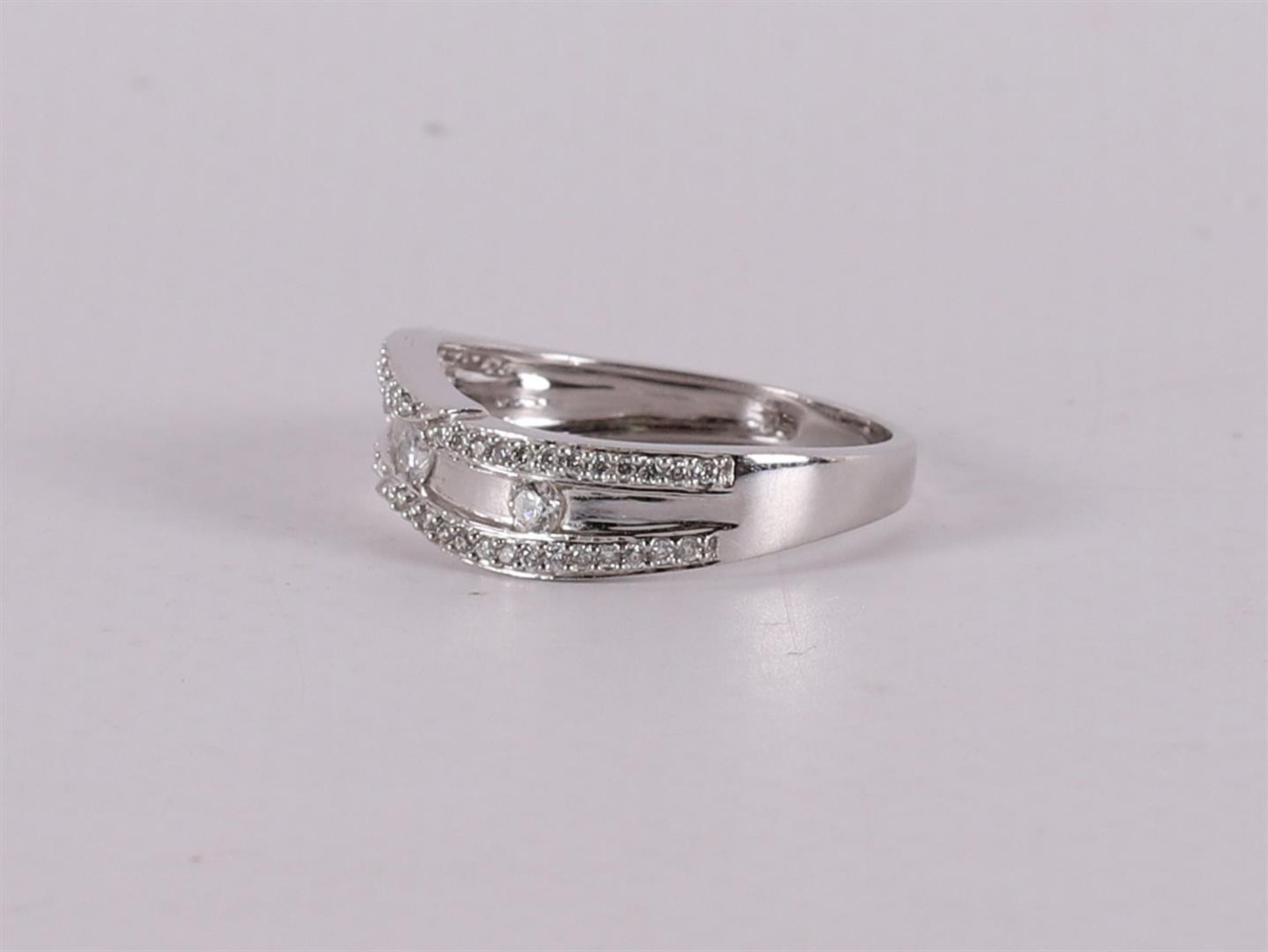 An 18 kt white gold band ring with 3 brilliants and 54 smaller ones. - Image 2 of 2