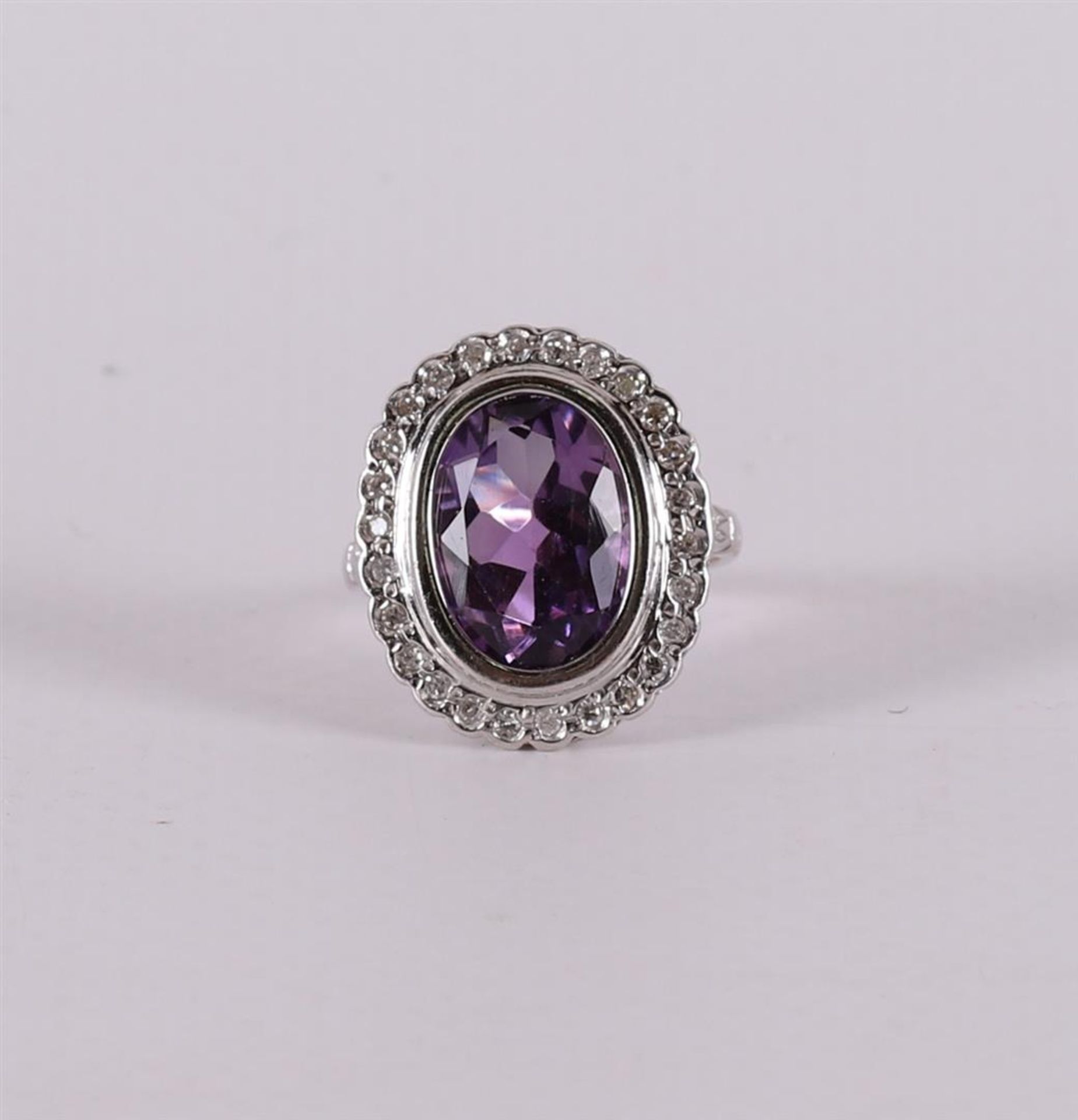 An 18 carat gold ring with an oval faceted amethyst and diamonds.