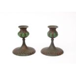 Tiffany Studios, New York A pair of patinated bronze candlesticks with green glass blown tops,
