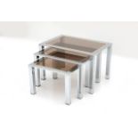 Hollywood Regency A three-part nest of tables, chromium plated metal and brass, with smoke-