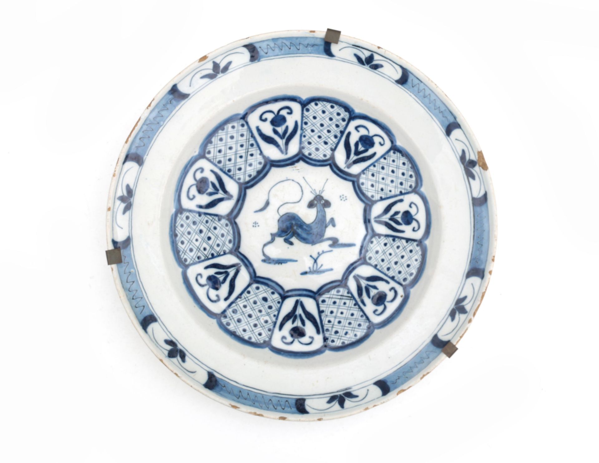 A large blue and white earthenware dish, decorated with flowers and a fantasy animal, probably