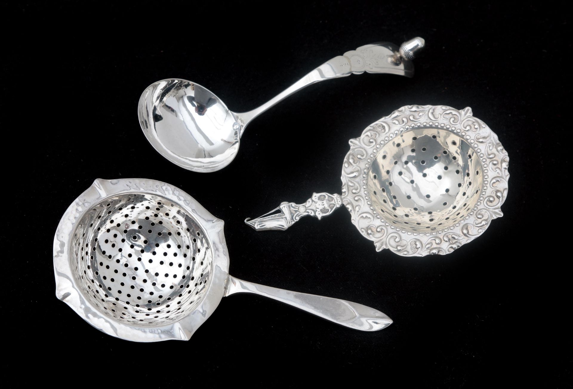 A pair of 2nd grade silver tea strainers and a silver cream spoon. First half of the 20th century.