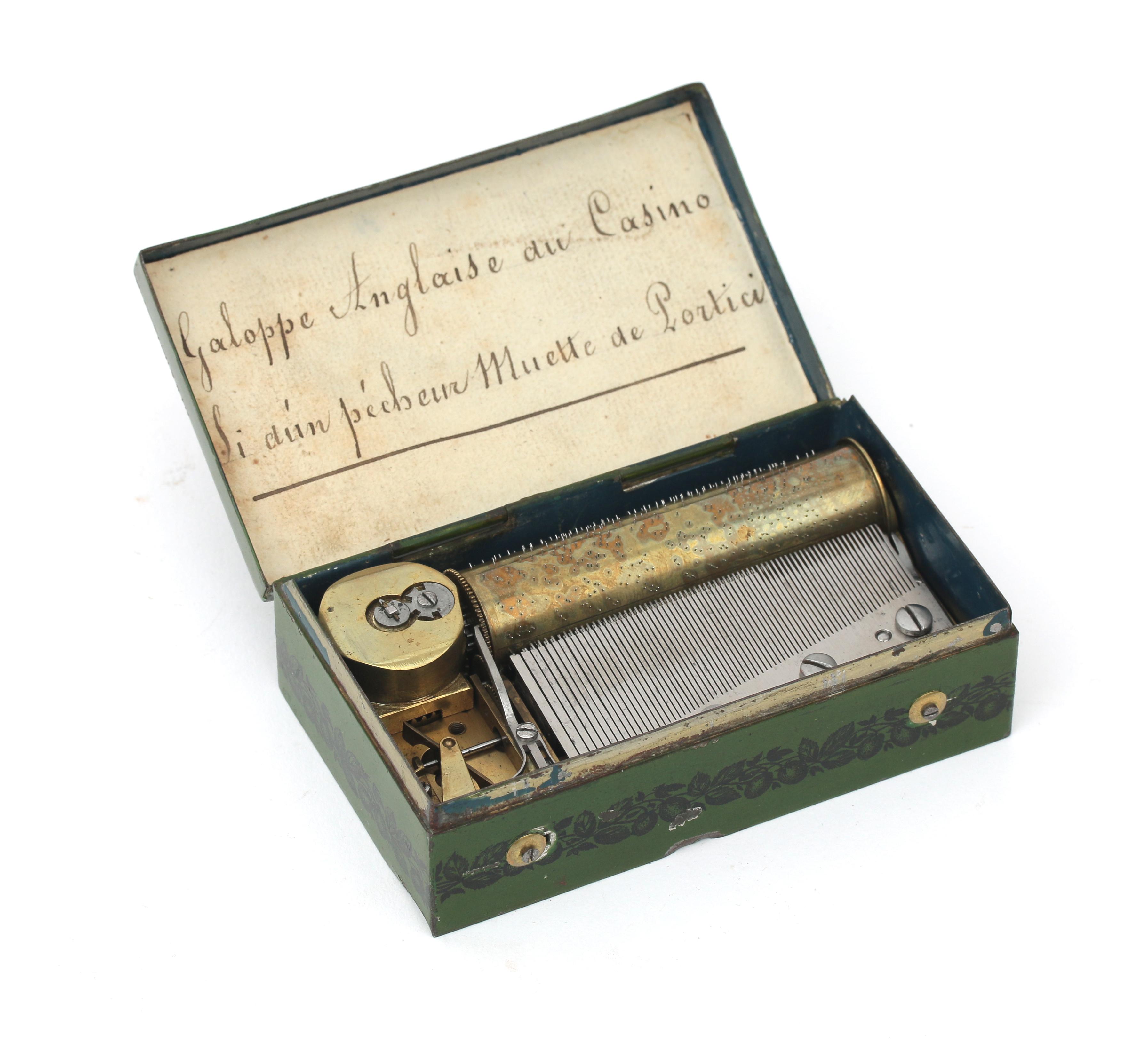 A Swiss souvenir cylinder music box in green tin case decorated with a landscape with the text: