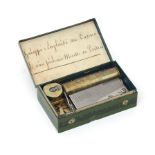 A Swiss souvenir cylinder music box in green tin case decorated with a landscape with the text: