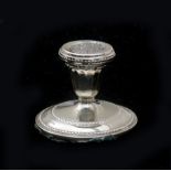 A silver candlestick on a round foot with a pearl rim. With traces of use and slightly loosened