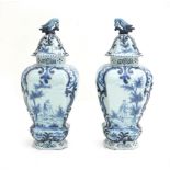 A pair of large Delft blue and white covered vases, decorated with foliate motifs, a man with a