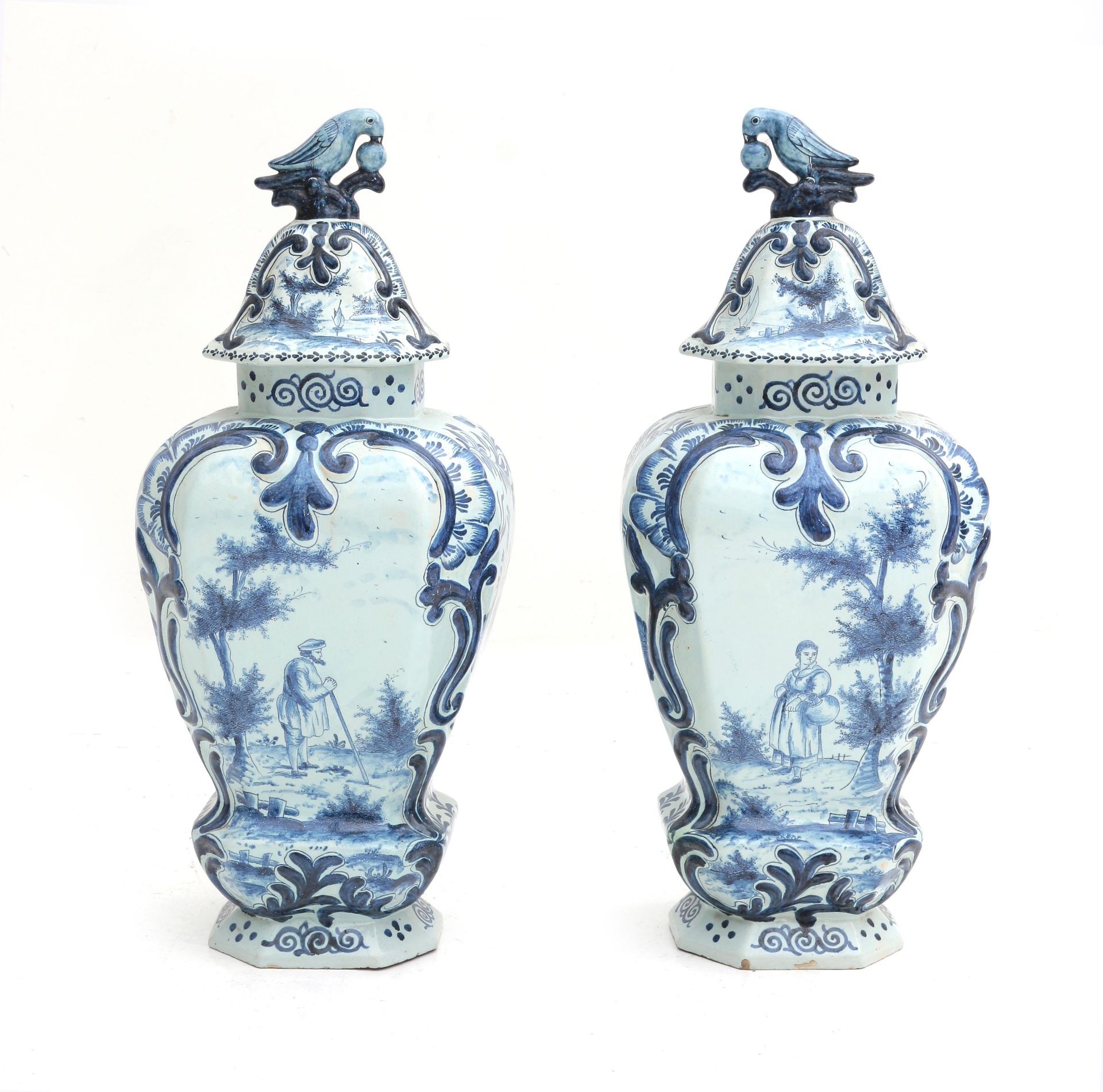 A pair of large Delft blue and white covered vases, decorated with foliate motifs, a man with a