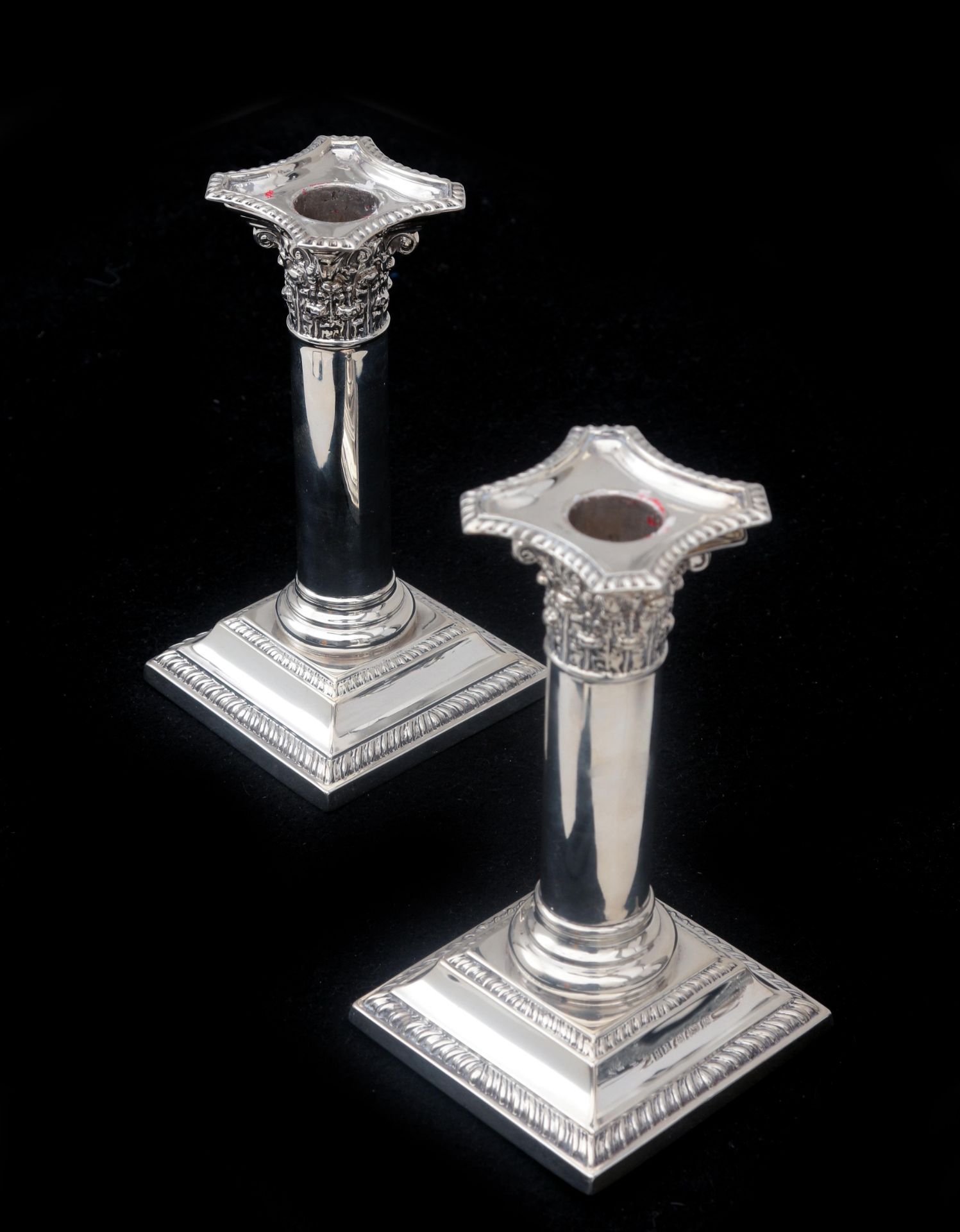 A pair of silver candlesticks, in the shape of Corinthian columns with a smooth shaft on a square