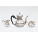 A three piece 835 silver tea service, comprising: teapot with wooden scroll handle, two handled