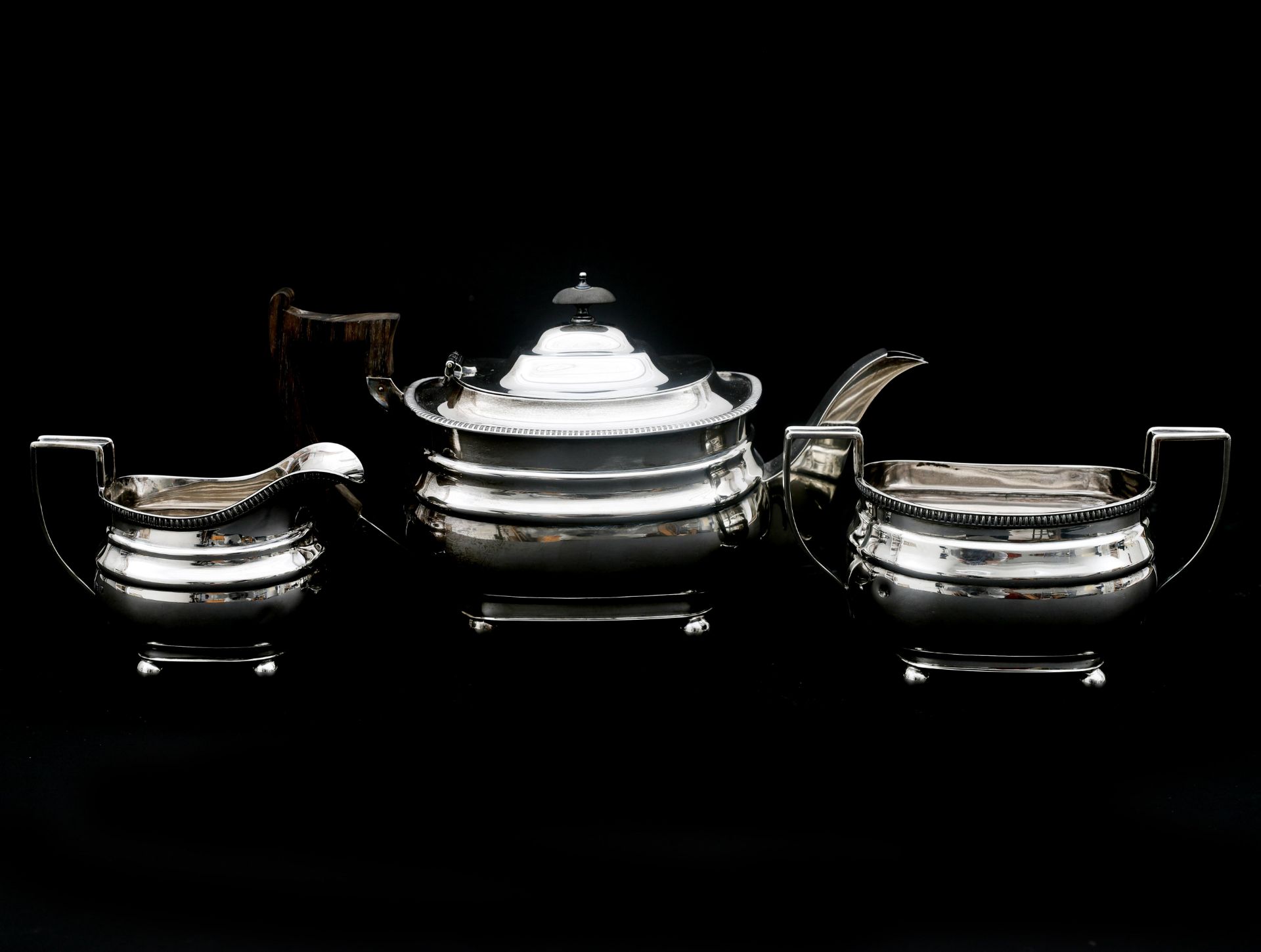 A three-piece Sterling silver English tea service, with a cord rim and resting on four ball feet