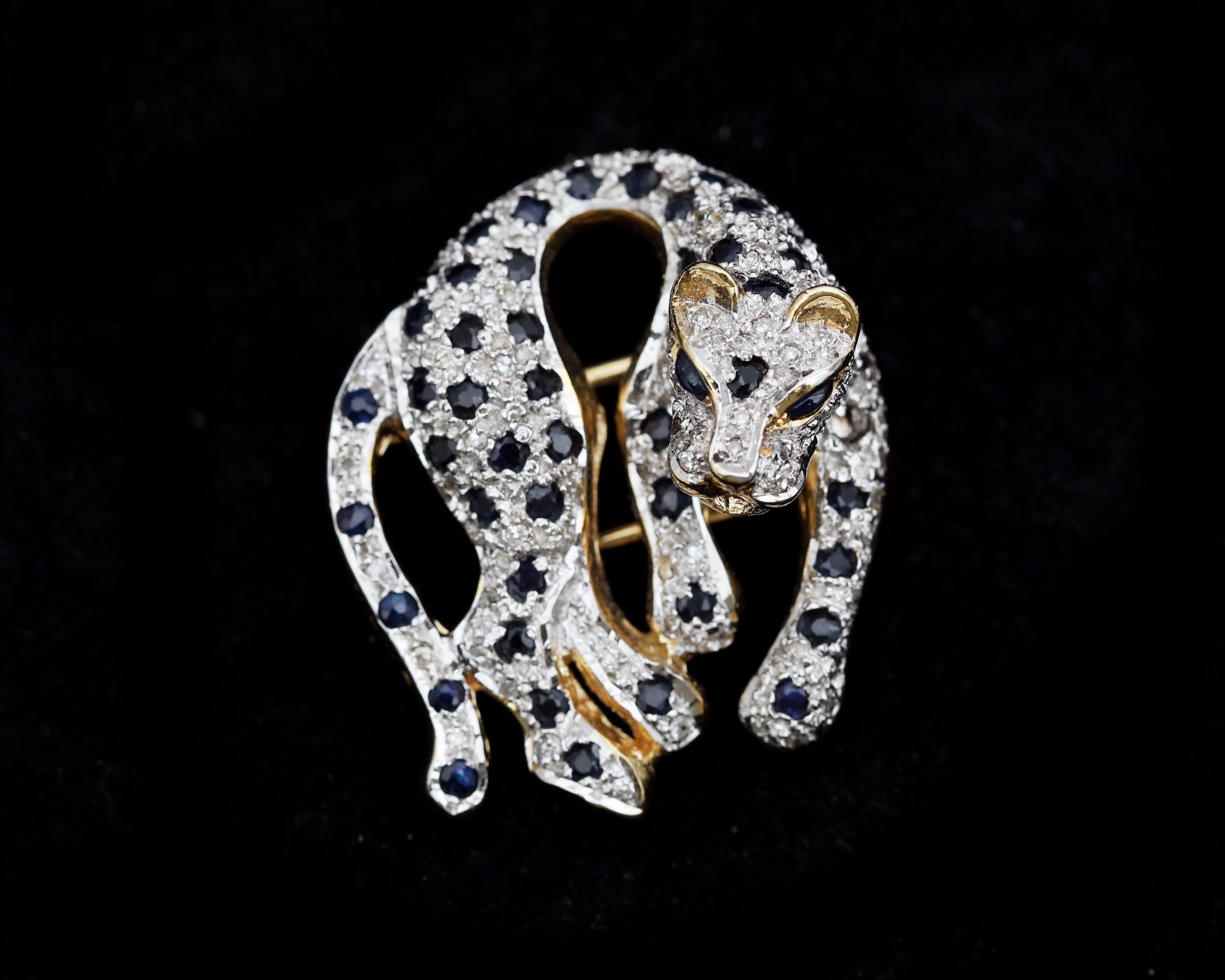 A 14 karat gold panther brooch pavé set with diamonds and sapphire. 