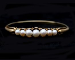A 14 karat gold bangle with Akoya pearls 