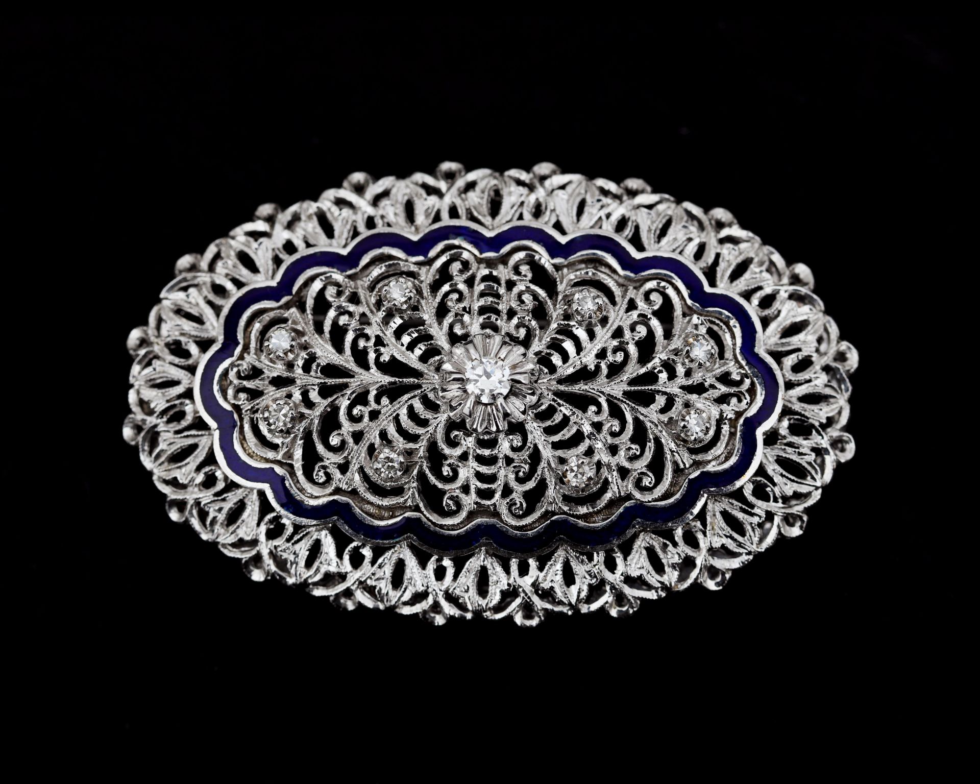 An 18 karat white gold in floral decor openwork oval brooch