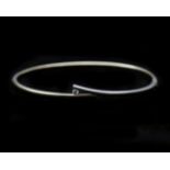 A 14 karat bicolor solid yellow and white gold bangle, set with diamond