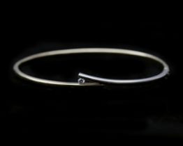 A 14 karat bicolor solid yellow and white gold bangle, set with diamond 