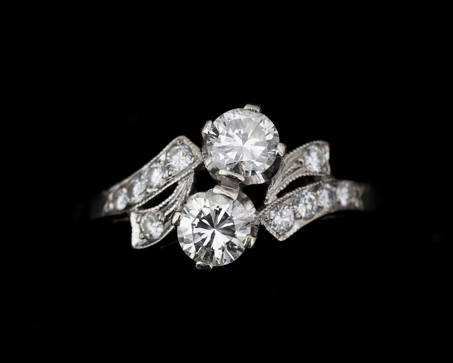 A 14 karat white gold diamond cross over ring