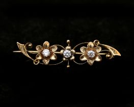 A 14 karat gold floral decorated brooch set with three cubic zirconias 