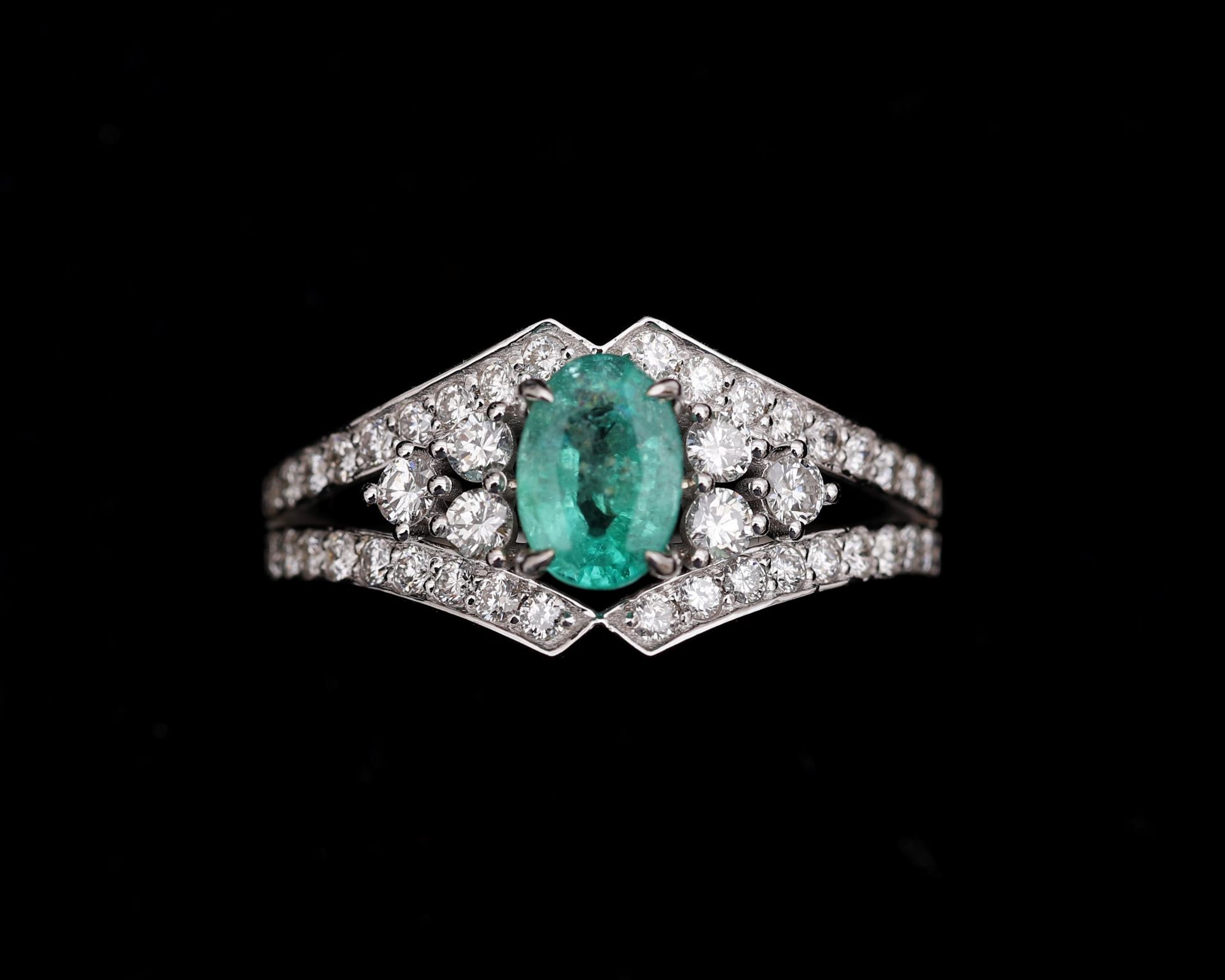 An 18 karat white gold ring centrally set with emerald and diamonds 