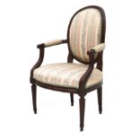 A nutwood Louis XVI armchair, late 19th century. The oval back profiled, the armrests with similar