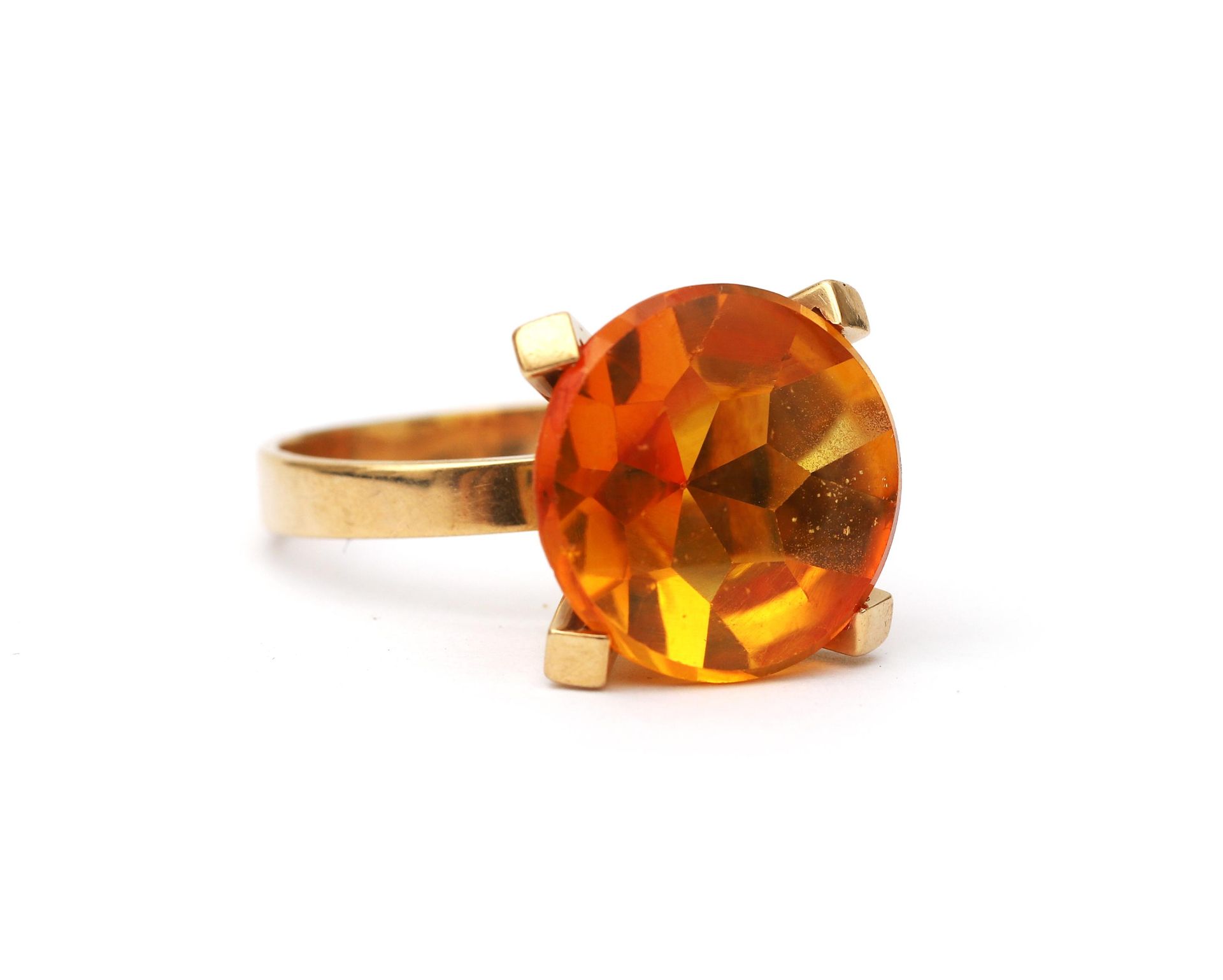 A 14 karat gold orange stone solitaire ring. Featuring an orange transparant buff top cut stone,