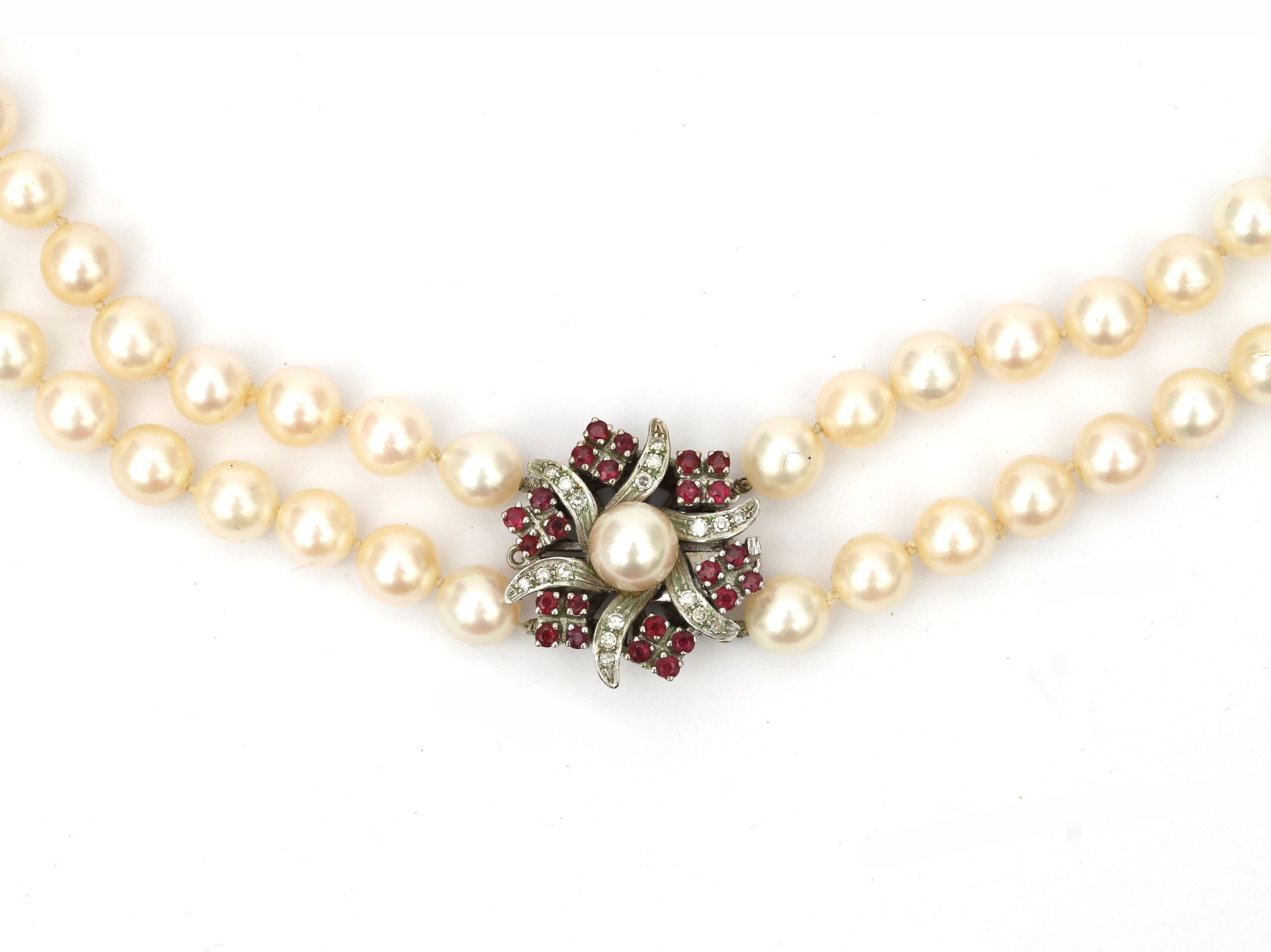 A cultured pearl necklace to a ruby and diamond white gold clasp. Featuring two knotted strands of