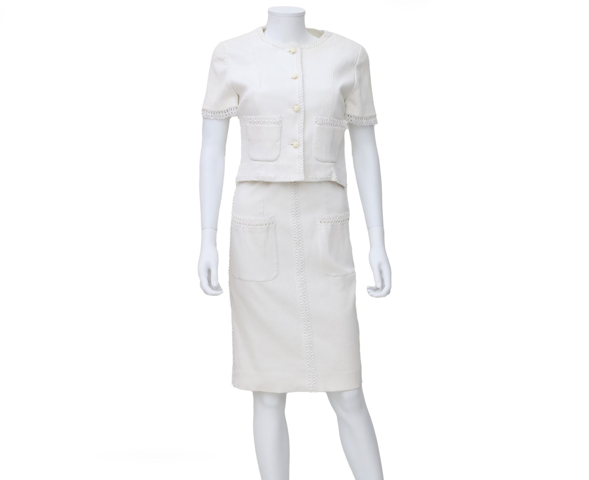 A white Chanel Boutique ensemble of a dress and jacket. The edges of the dress and jacket are made