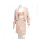 A Chanel Boutique tweed ensemble a white with soft pink bustier, blazer and skirt. The jacket has