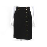 A black Chanel skirt with gold colored buttons. The buttons have four-leaf clover details and run