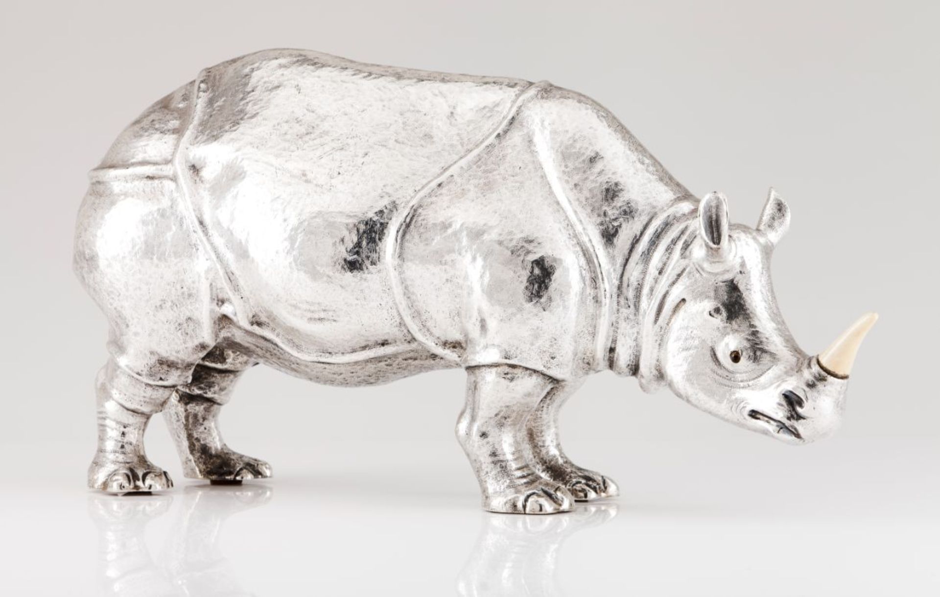 A large Manuel Alcino rhinocerosRepoussé and chiselled Portuguese silver sculpture with applied