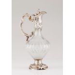 A jug with coverCut glass bulging body with silver mounts Handle, lip and base of foliage,