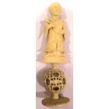 Hand carved ivory figurine on plinth with puzzle ball below, H: 15 cm. P&P Group 1 (£14+VAT for