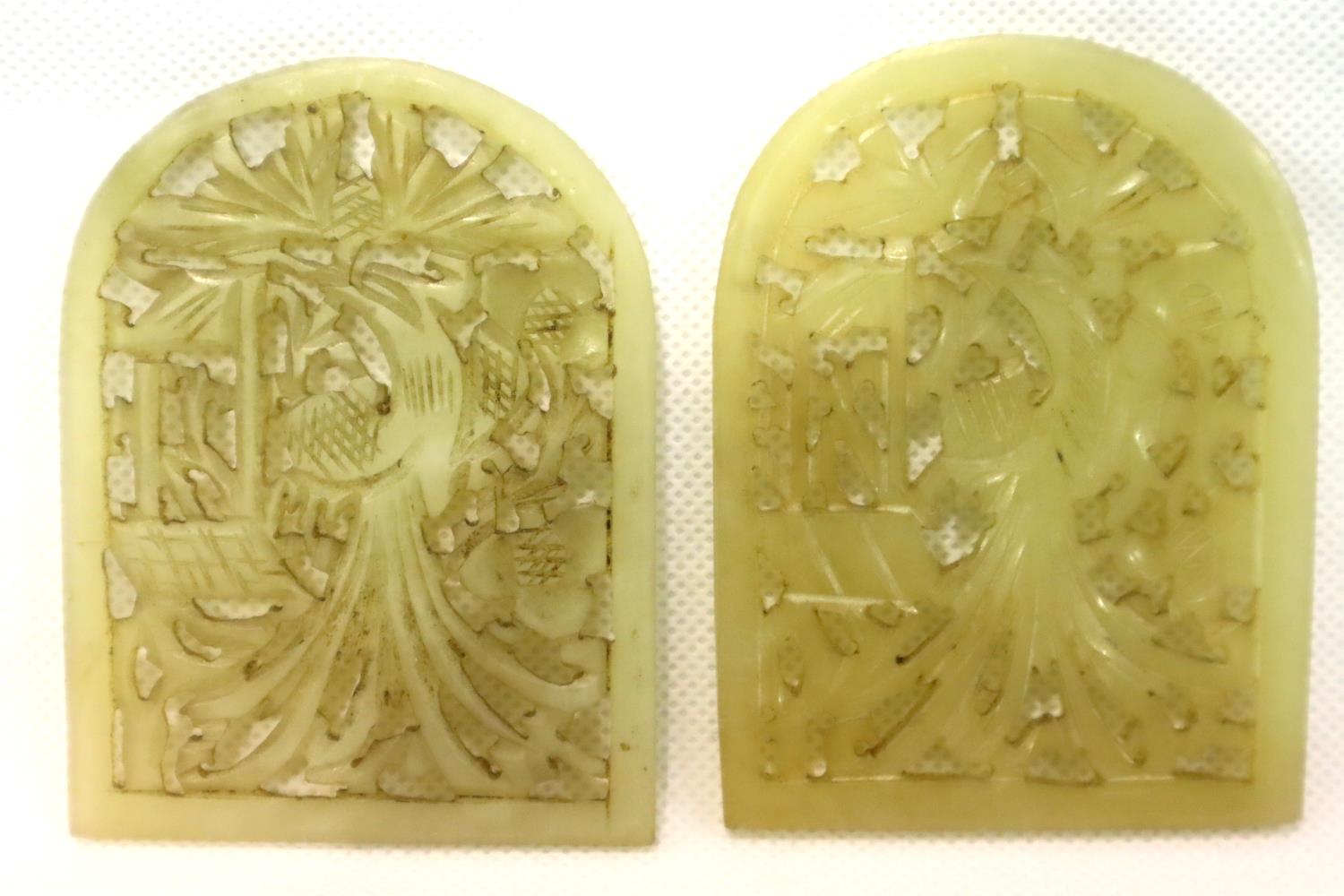 A pair of Chinese pale celadon hardstone arched amulets, each with reticulated floral design